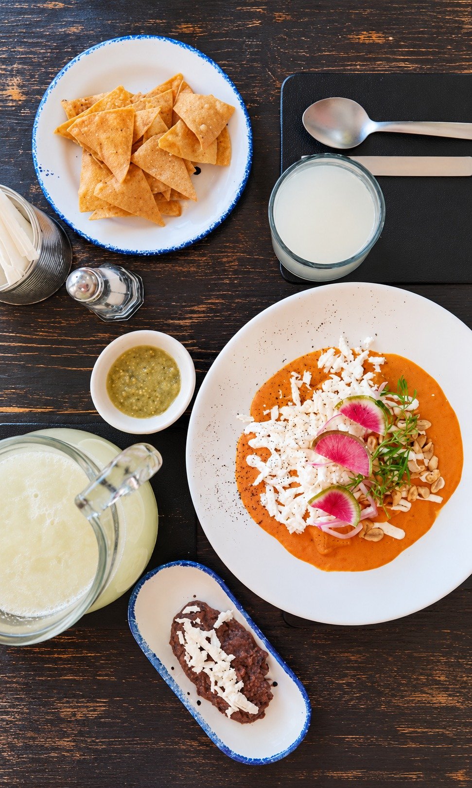 Mesa servida con platillo mexicano, bebidas y acompañamientos de Olivos